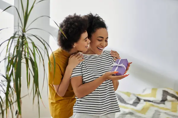 A delighted couple shares a heartfelt moment while opening a surprise gift. — Stock Photo