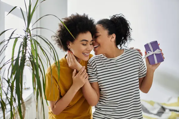 Un couple amoureux échange sourires et rires tout en partageant un cadeau. — Photo de stock