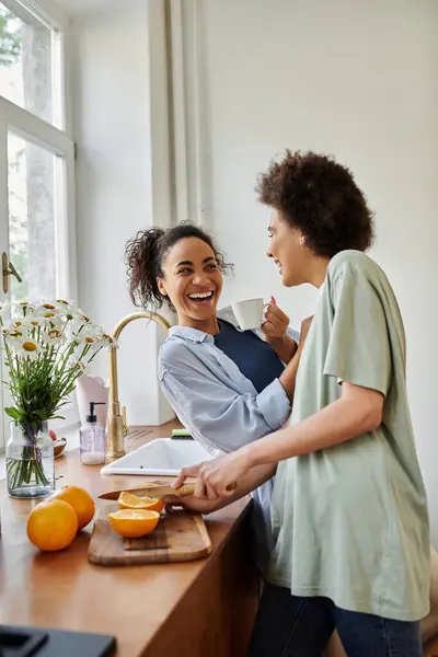 Two women share laughter and joy while cooking in their cozy kitchen. — Stock Photo