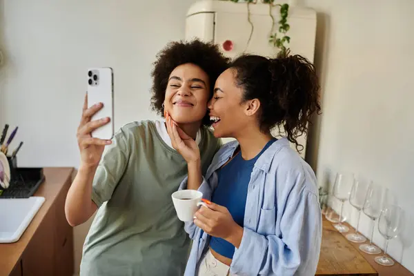 Due donne condividono un momento allegro insieme mentre si godono il caffè a casa. — Foto stock