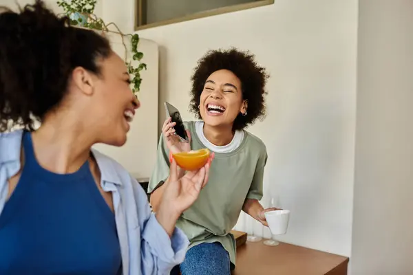 A happy couple shares laughter while sipping coffee and enjoying fruit at home. — Stock Photo