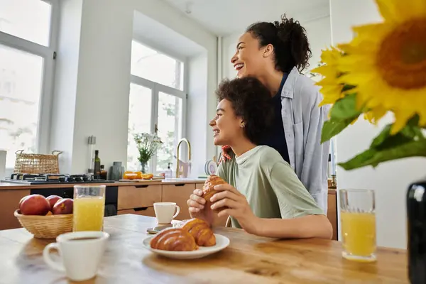 Two women share laughter and breakfast, surrounded by warmth and sunlight. — Stock Photo