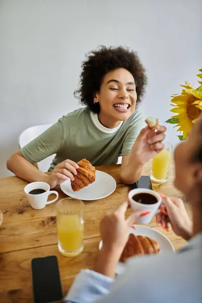 A happy couple shares breakfast, savoring croissants and warm drinks together. — Stock Photo