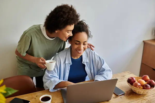 A loving couple shares laughter while working together at their cozy kitchen table. — Stock Photo