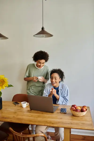 Riendo pareja disfruta de un momento alegre mientras trabaja en un ordenador portátil en casa. - foto de stock