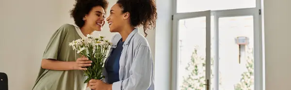 A loving couple embraces while sharing flowers in their warm living space. — Stock Photo