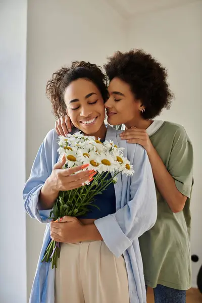 A couple shares a loving embrace while enjoying a bouquet of daisies. — Stock Photo