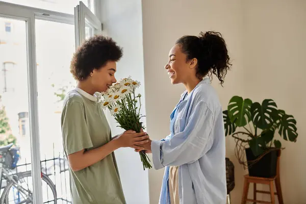 A couple exchanges a bouquet, sharing smiles and love in a cozy setting. — Stock Photo