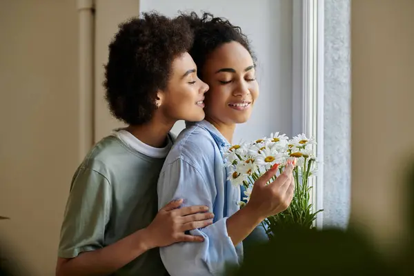 Una coppia amorevole condivide un momento tenero mentre tiene le margherite vicino alla finestra. — Foto stock