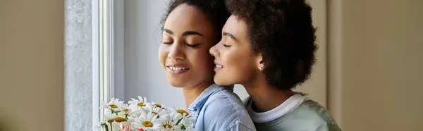 A loving couple shares a sweet embrace while holding a bouquet of daisies. — Stock Photo