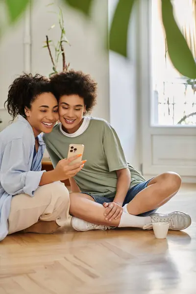 Two women share laughter while watching something on a smartphone together. — Stock Photo