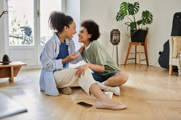 A joyful lesbian couple shares laughter and love in their cozy living space. — Stock Photo