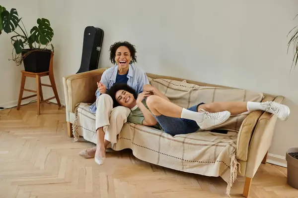 A loving couple shares laughter together on their couch in a warm, inviting setting. — Stock Photo