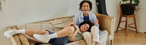 Two partners share laughter and joy on a comfortable couch. — Stock Photo