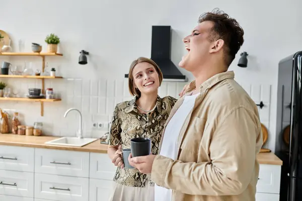 Two friends share a joyful moment while sipping drinks in a bright kitchen. — Stock Photo
