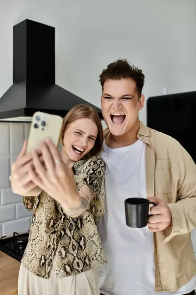 Two friends share laughter while taking a playful selfie in their cozy kitchen. — Stock Photo