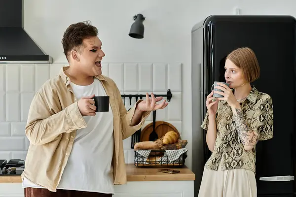 Due amici condividono un gioioso momento di caffè a casa, abbracciando i loro stili unici. — Foto stock