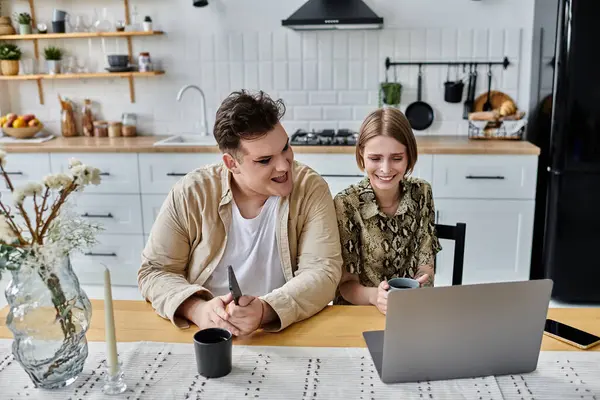 A joyful moment shared over a laptop in a modern kitchen. — Stock Photo