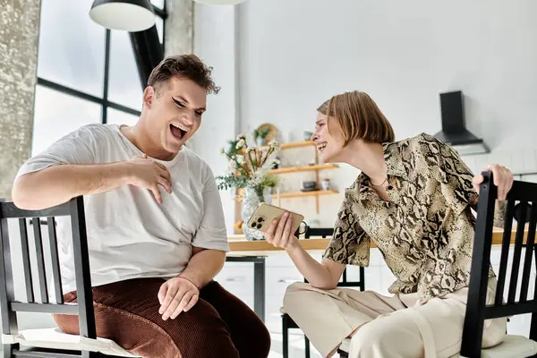 Two friends laughing together while sharing a fun moment at home. — Stock Photo