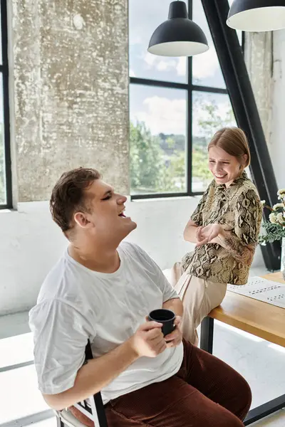 Two friends share laughter while sipping beverages in a cozy, bright space. — Stock Photo