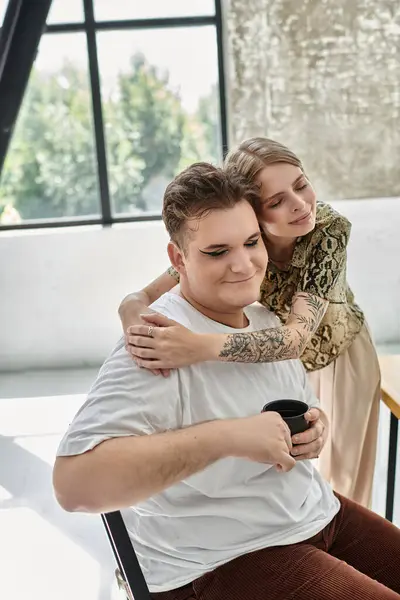 Eine stilvolle Person genießt eine herzliche Umarmung mit einem Freund, während sie Kaffee genießt. — Stockfoto