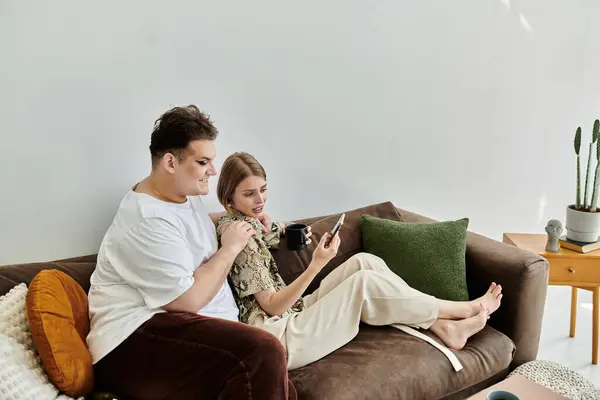 Two friends share laughter and warmth while engaging with their devices. — Stock Photo