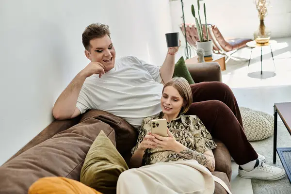 Two friends laugh together while sharing a cozy moment on the couch. — Stock Photo