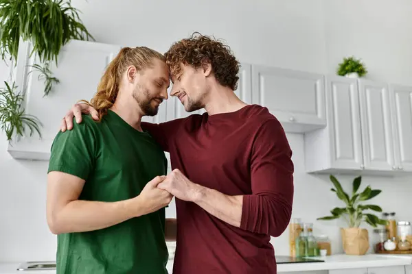 A tender embrace shared by a gay couple in their bright kitchen. — Stock Photo