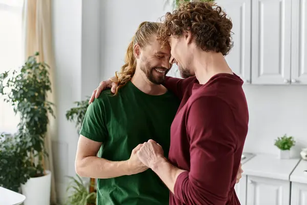 Due uomini si abbracciano amorevolmente, condividendo un momento di felicità nella loro cucina. — Foto stock