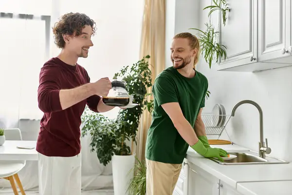 A couple shares coffee and laughs while cleaning up in their cozy kitchen. — Stock Photo