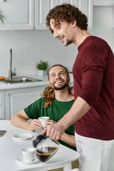 Two partners share laughter while brewing coffee in their warm kitchen. — Stock Photo