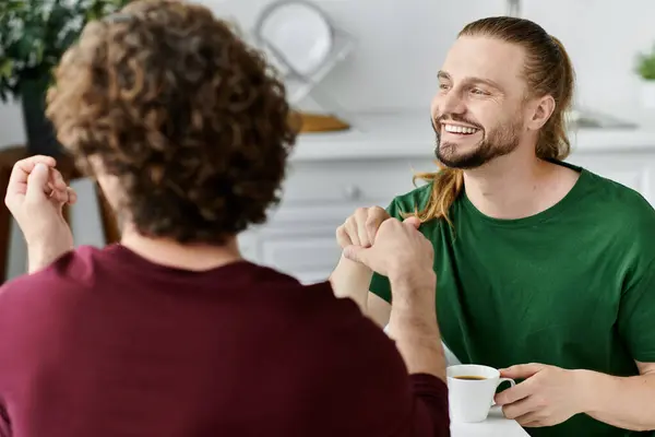 Due partner condividono risate e calore davanti al caffè nella loro accogliente casa. — Foto stock