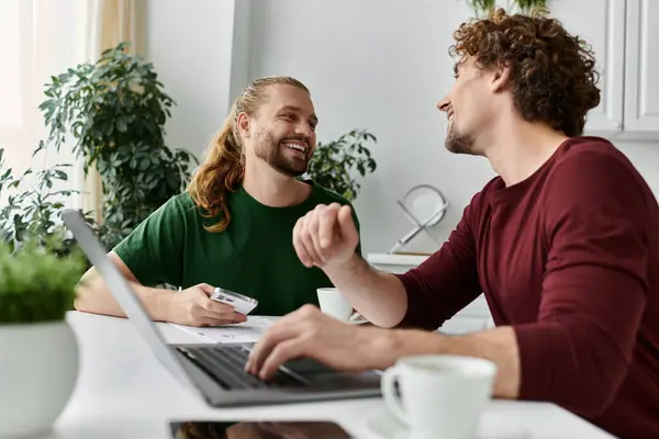 Two men share laughter and love over coffee at their kitchen table. — Stock Photo