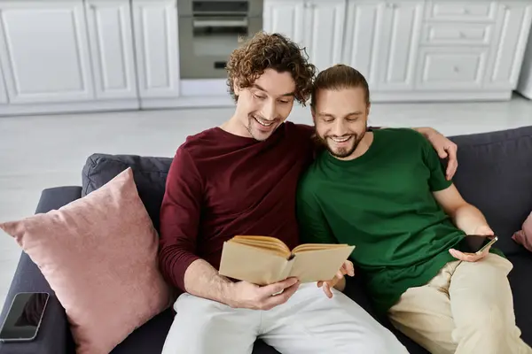 Two men share a cozy reading moment, enjoying each other at home. — Stock Photo