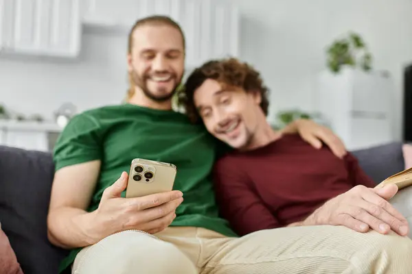 Two partners share laughter and joy while using their phone on the couch. — Stock Photo