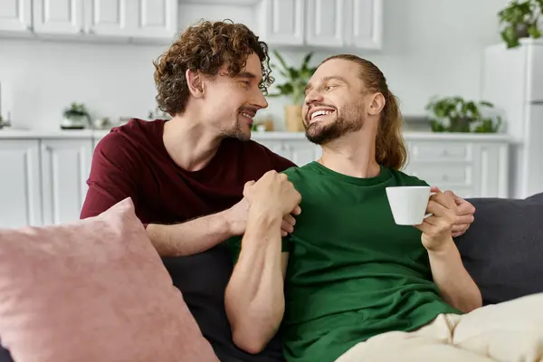 A loving couple shares laughter and coffee on their cozy sofa. — Stock Photo
