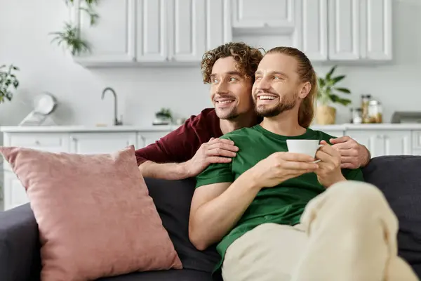 A happy couple enjoys each other while sipping coffee on the couch. — Stock Photo