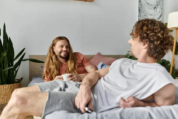 Two partners share joyful conversations over coffee in their cozy bedroom. — Stock Photo