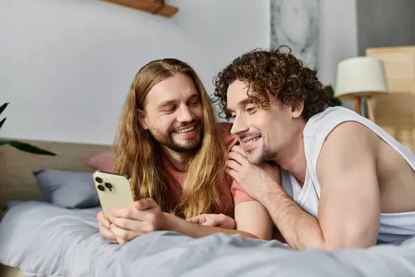 Two men share a joyful moment, exploring their phones side by side. — Stock Photo