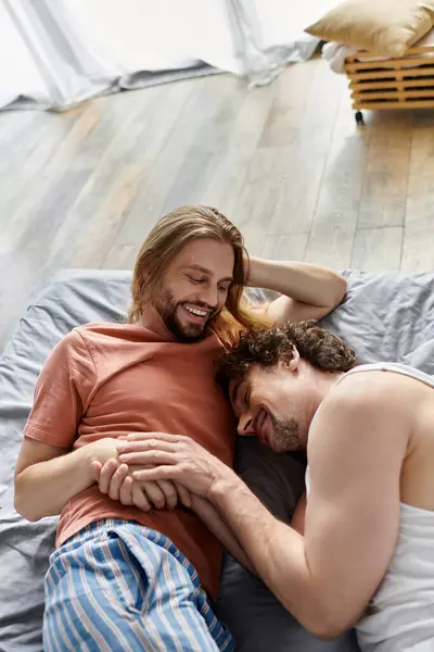 Due uomini condividono risate e calore mentre si rilassano su un letto morbido. — Foto stock