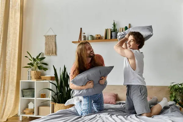 Two joyful partners engage in a playful pillow fight at home. — Stock Photo