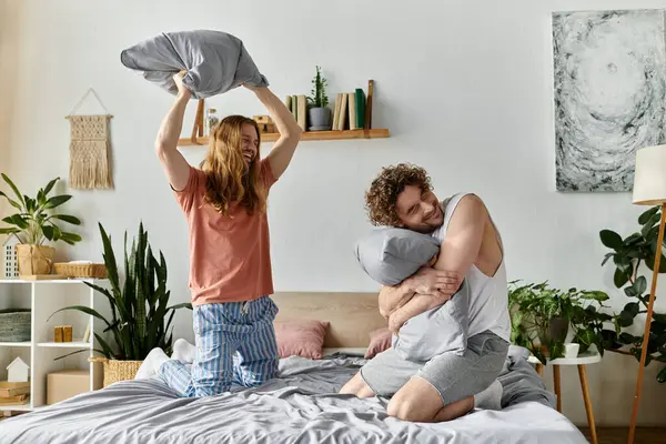 A happy couple shares laughter and playful pillow fights in their bedroom. — Stock Photo