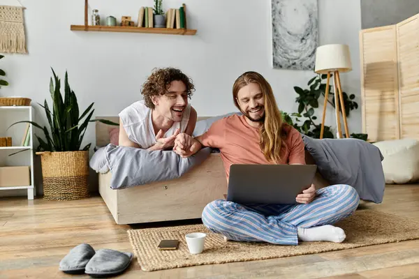 Two partners share laughter and connection while using a laptop in their cozy living space. — Stock Photo