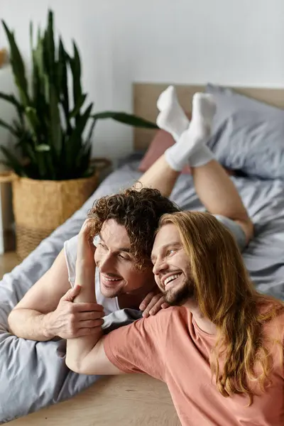 A joyful gay couple enjoys each other on their cozy bed. — Stock Photo
