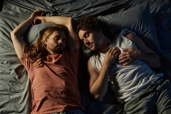 Dos parejas comparten un momento íntimo acostados juntos en la cama en casa. - foto de stock