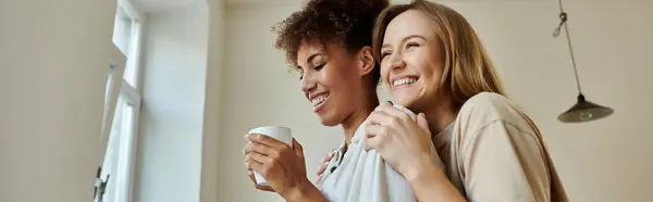 Two partners share laughter and warmth while sipping drinks together indoors. — Stock Photo