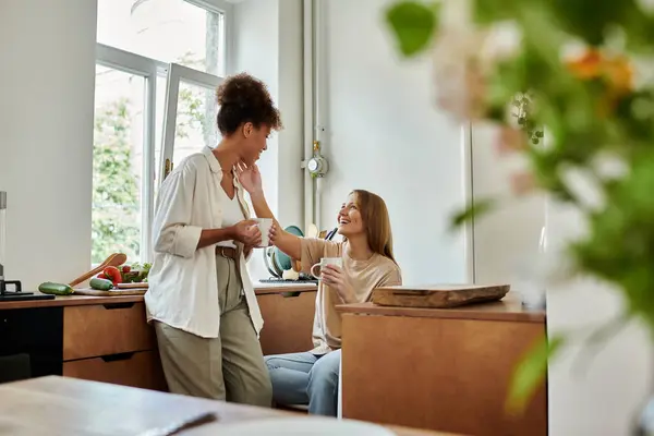 A lovely couple shares laughter and affection over drinks in their kitchen. — Stock Photo