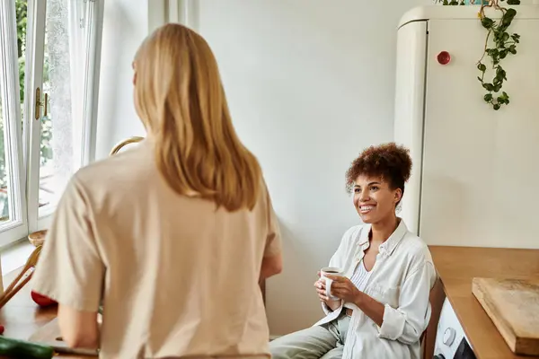 A cheerful couple enjoys a warm drink together in their stylish kitchen. — Stock Photo