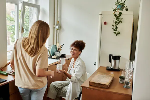 Dos socios comparten la risa y el calor en su cocina soleada. — Stock Photo