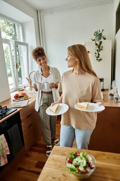 Joyful partners share moments while preparing a meal in their sunlit kitchen. — Stock Photo